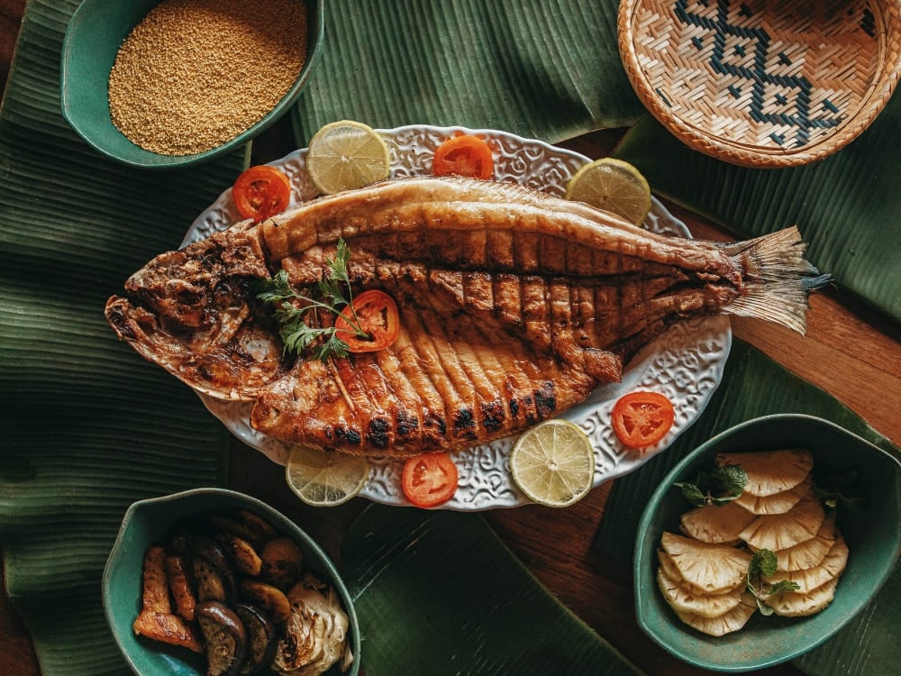 Photo: Felipe Castellari Whole grilled fish served on banana leaves with farofa, lime and tomato in the Brazilian Amazon
