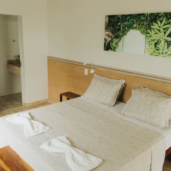 A comfortable guesthouse bedroom with a neatly made double bed and botanical artwork in Jalapão.