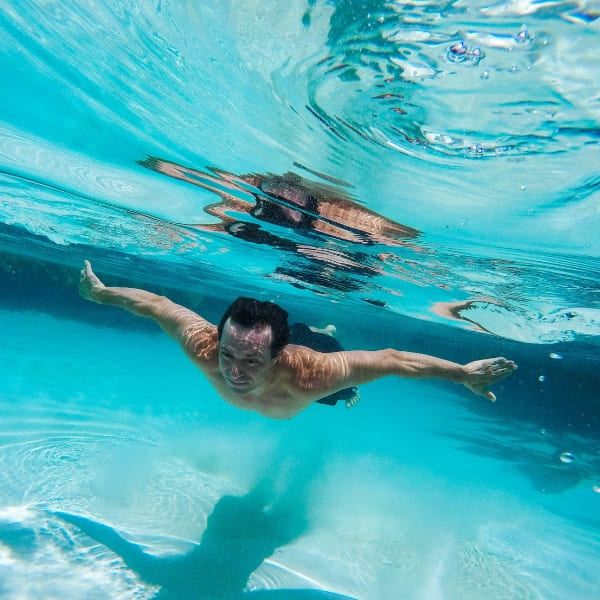 A man swims underwater in the crystal-clear blue waters of a Jalapão natural spring.
