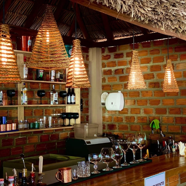 A rustic guesthouse bar area decorated with woven straw lamps and brick walls in Jalapão