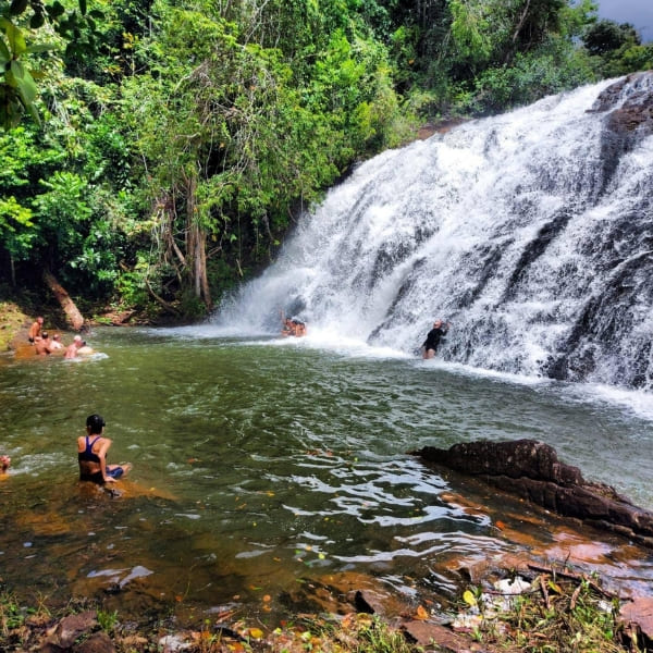 People swim and relax in a natural pool at the base of the cascading Milagrosa Waterfall.