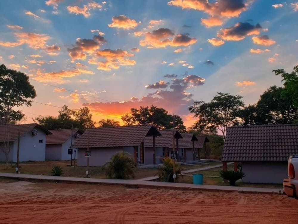 Row of cozy private chalets at Pousada Beira da Mata under a vibrant sunset sky.