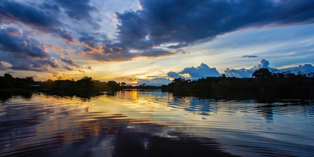 Beautiful sunset with clouds reflected in the calm waters of the Mamori River during an Amazon rainforest holiday.