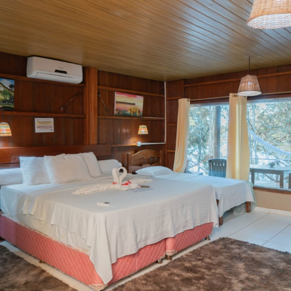 Comfortable interior of a wooden bungalow with two beds, air conditioning, and large glass windows.