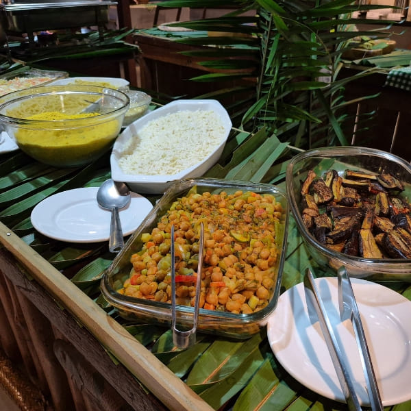 Homemade food dishes arranged on a rustic buffet decorated with banana leaves.