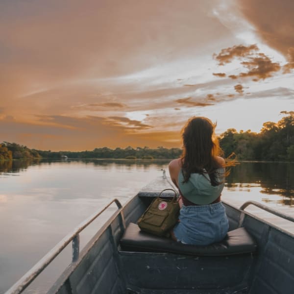 Woman sitting at the front of a motorized canoe watching the sunset on the Mamori River.