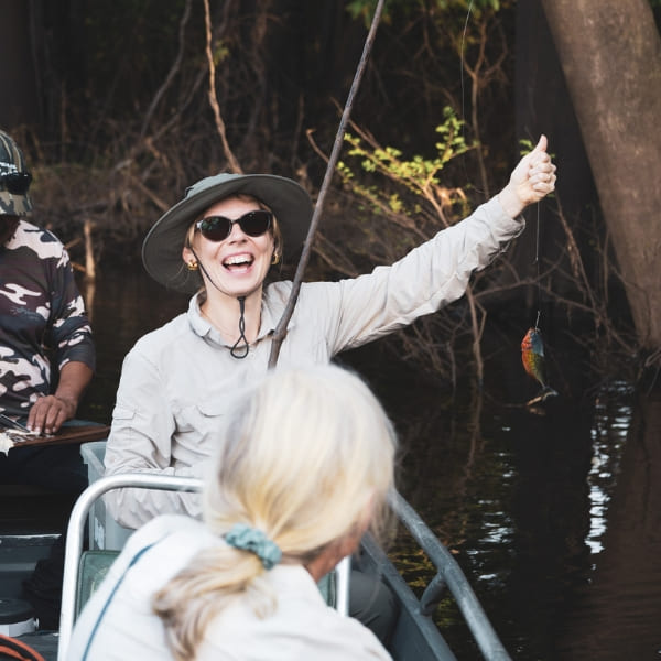 Smiling woman holding a fishing rod after catching a fish at Lake Tracajá.