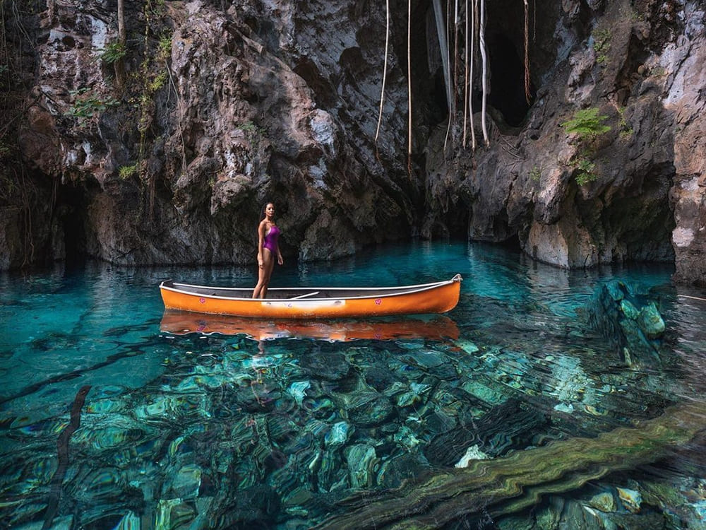 A woman stands on a canoe in the blue-green waters of the Japanese Lagoon during a 4-day Jalapão tour.