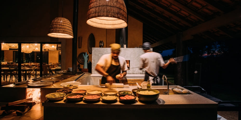 Chefs preparing fresh food in the Caiman Ecolodge restaurant kitchen, featuring an open wood-fired oven.