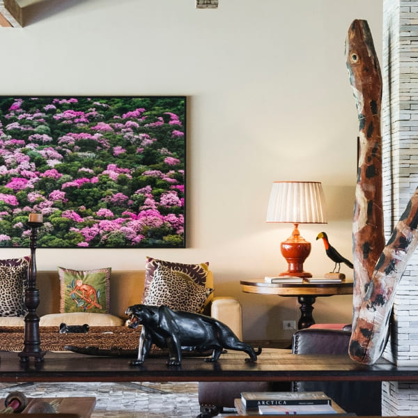 A rustic living room at Caiman Ecolodge decorated with carved animal sculptures and a vibrant nature painting for a luxury jaguar safari experience.