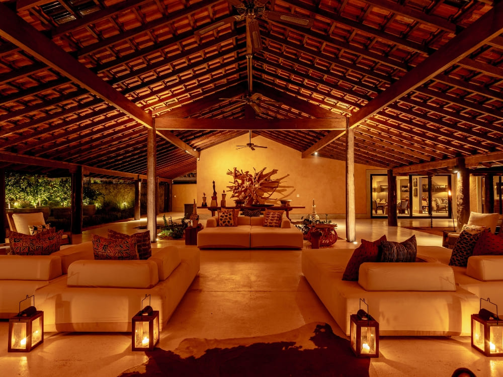 The elegant living room at Casa Caiman featuring warm lighting, large sofas, and a high wooden ceiling.