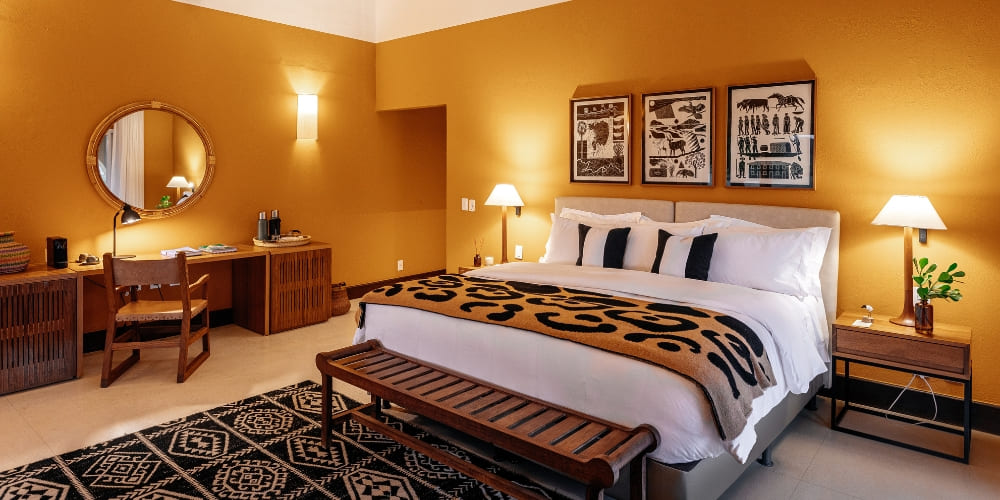 A cozy suite at Casa Caiman with a king-size bed, jaguar print blanket, and warm yellow walls.