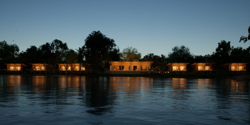 Exterior view of the luxurious Cordilheira bungalows lit up at dusk, situated along a serene lake.