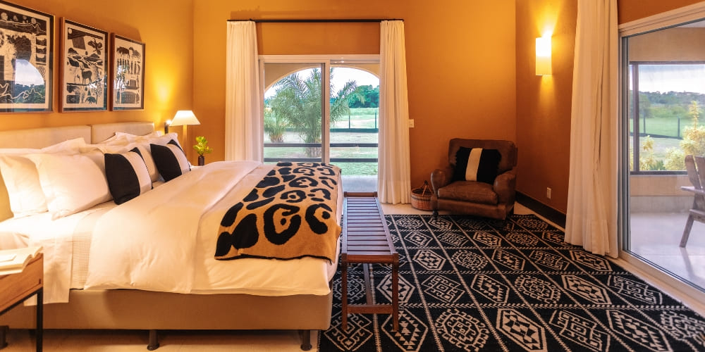 Une luxueuse suite de la Casa Caiman comprenant un lit king-size avec une couverture à imprimé jaguar, un tapis à motifs et un patio extérieur lumineux.