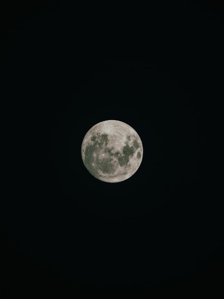 A bright, detailed full moon shines prominently against a completely black night sky.