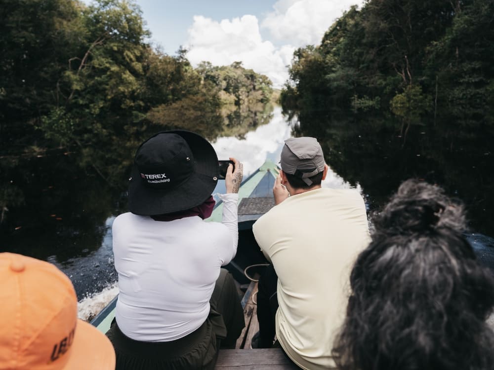 Passengers in a motorized canoe take pictures while navigating aquatic trails on the Ariau River to observe the wildlife.