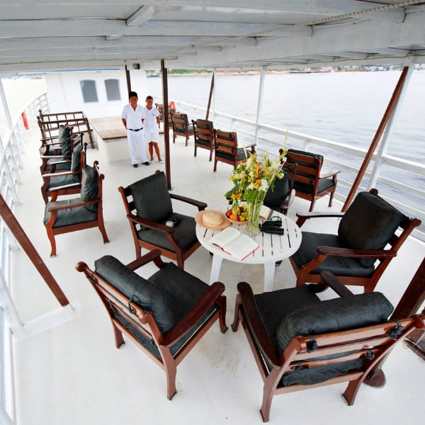 A woman sitting at a set table in the elegant wood-paneled dining room of the Tucano Amazon river cruise.