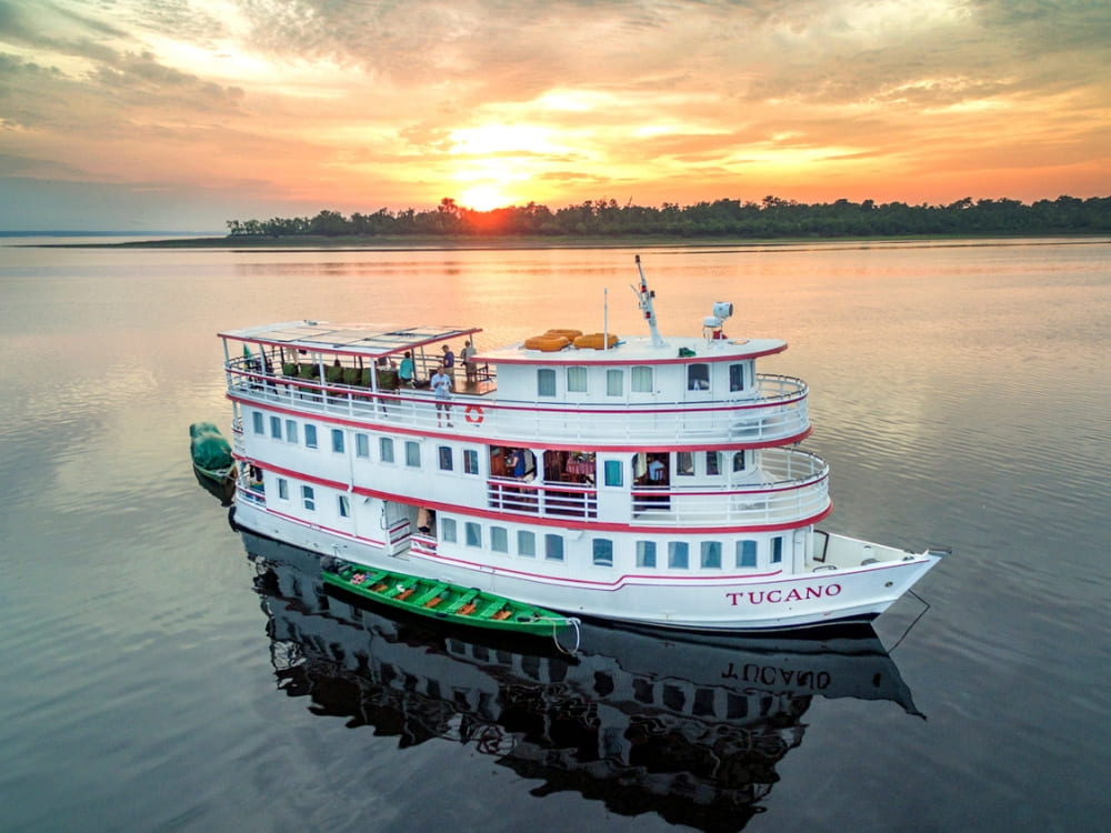  Aerial view of the three-floor vessel used for small ship Amazon river cruises floating on calm waters.