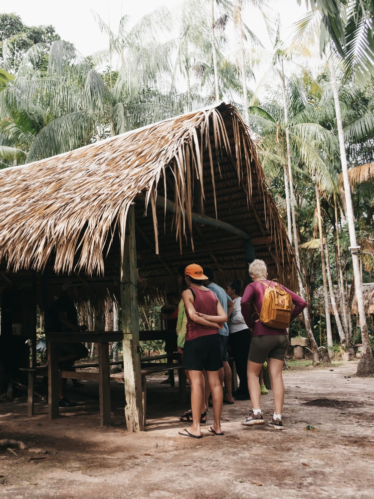 Tour guides and guests visit a thatched-roof structure at the Tumbira community in the Rio Negro Sustainable Development Reserve.