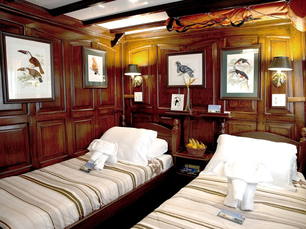 A cozy wood category cabin featuring elegant wood paneling, bird artwork, and two comfortable twin beds.