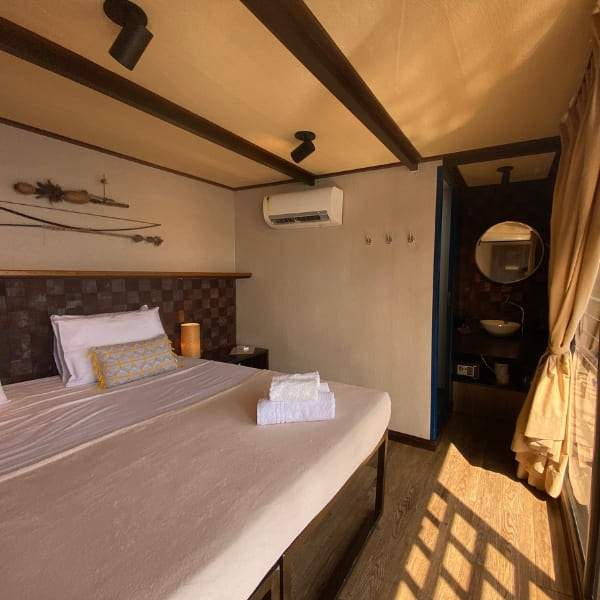 Elegant cabin interior on an Amazon river cruise featuring a king-size bed and large windows viewing the forest.