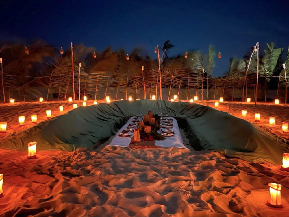 A candlelit dining setup on a sandy river beach in the Amazon for a special luau dinner under the stars, a highlight of the river cruise.