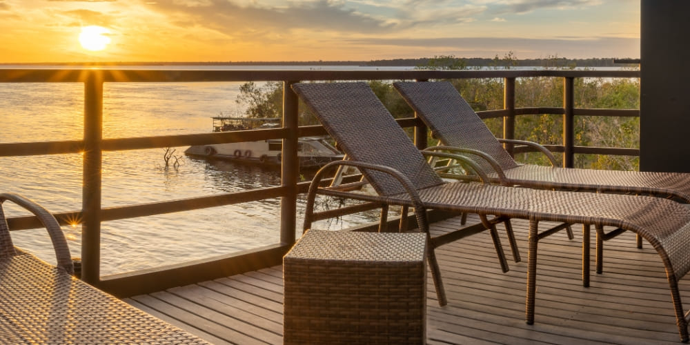 Spacious sun deck of the Zaltana riverboat with wooden lounge chairs overlooking the river, perfect for relaxing during the Amazon expedition.