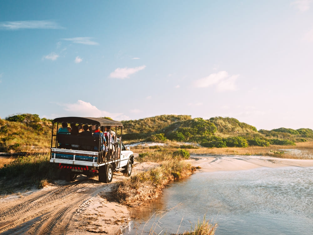 Un véhicule 4x4 transporte des touristes sur une piste sablonneuse menant au parc national des Lençóis Maranhenses.