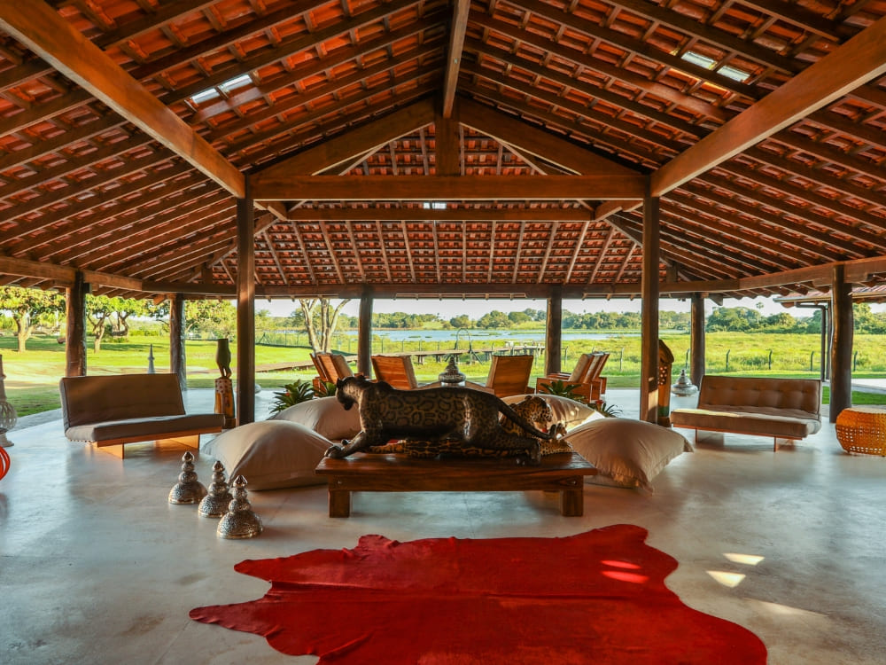 The luxurious interior of Caiman lodge features a wooden roof, comfortable seating areas, and a large jaguar statue.
