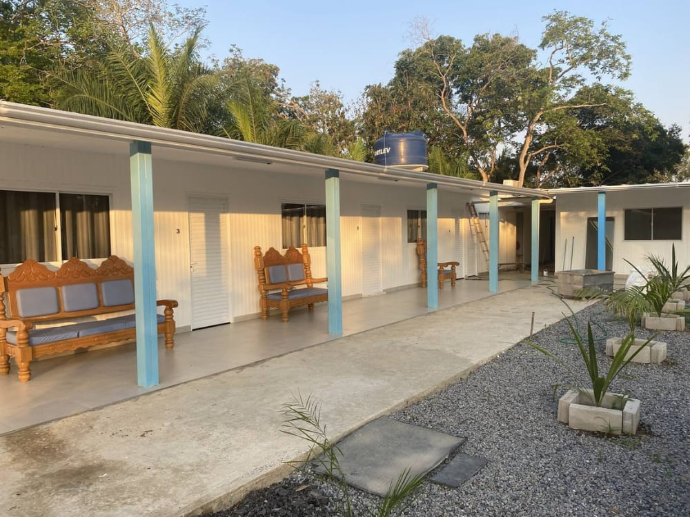 The exterior courtyard of Dona Onça lodge shows rustic accommodations with wooden benches in Porto Jofre.