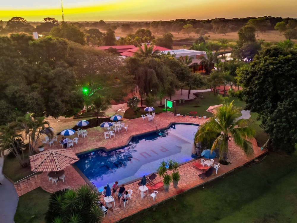 Guests relax near the outdoor swimming pool at Piuval lodge during a colorful sunset in the Northern Pantanal.