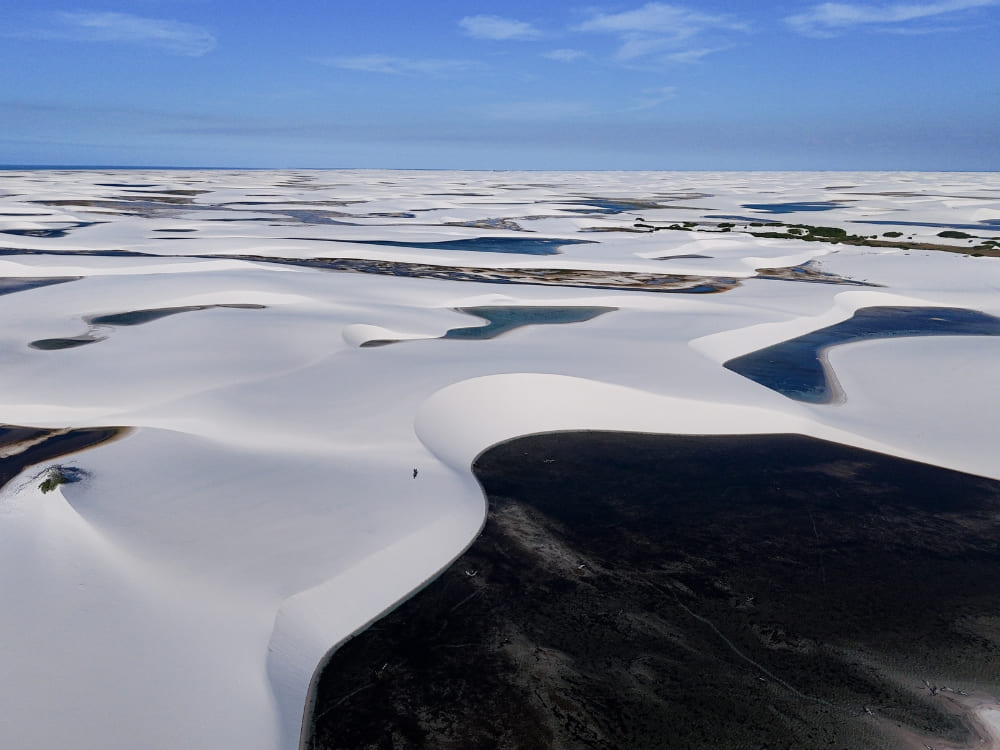 Un vaste paysage montre des milliers de lagunes d’eau de pluie dispersées entre les dunes de sable blanc du parc national des Lençóis Maranhenses.