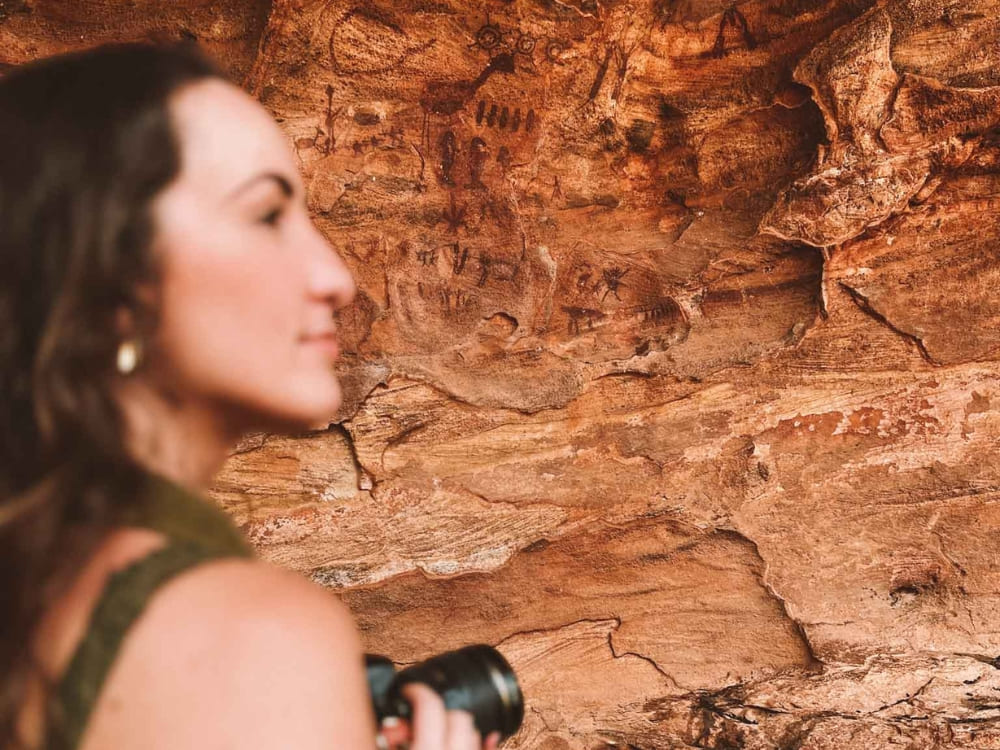 Woman viewing ancient cave paintings on a rock wall inside Serra da Capivara National Park. 