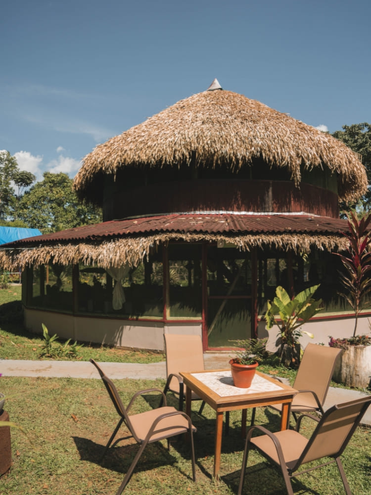 An outdoor seating area with chairs and a table outside the restaurant at Amazon Turtle Lodge.