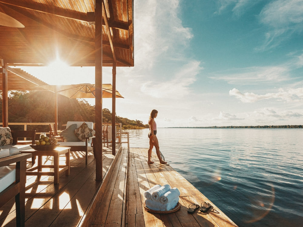 A woman relaxes on a wooden floating deck over the river at Anavilhanas Jungle Lodge, one of the best Amazon lodges in Brazil. A woman relaxes on a wooden floating deck over the river at Anavilhanas Jungle Lodge, one of the best Amazon lodges in Brazil.