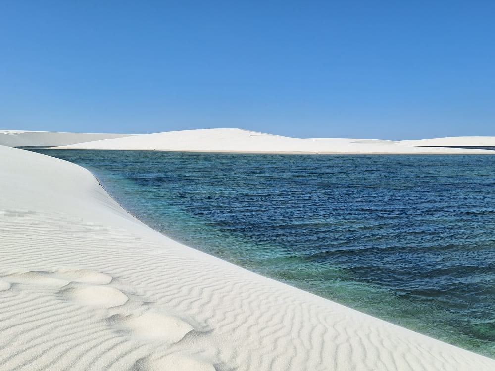 Turquoise freshwater lagoons nestled between vast white sand dunes in Lençóis Maranhenses National Park.
