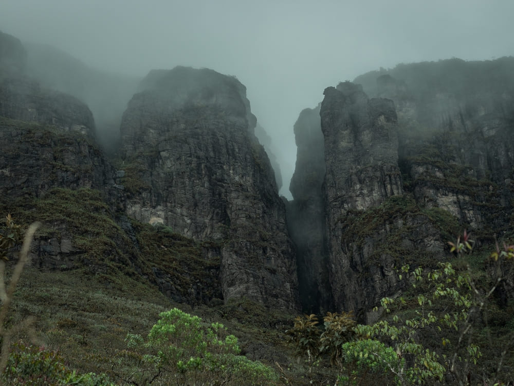 The dark, rocky cliffs of Pico da Neblina, Brazil's highest peak, shrouded in mist within the Amazon Rainforest.