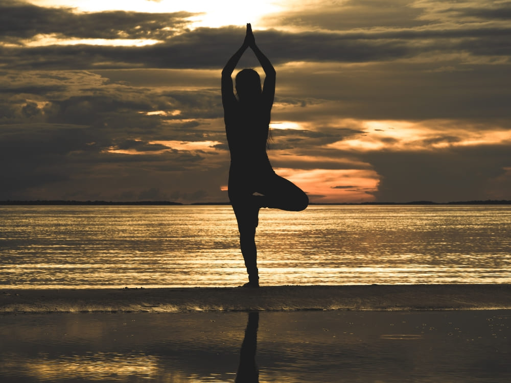 Silhouet van een persoon die een yoga-boomhouding doet op een rivierstrand in de Amazone bij zonsondergang. Silhouet van een persoon die een yoga-boomhouding doet op een rivierstrand in de Amazone bij zonsondergang.