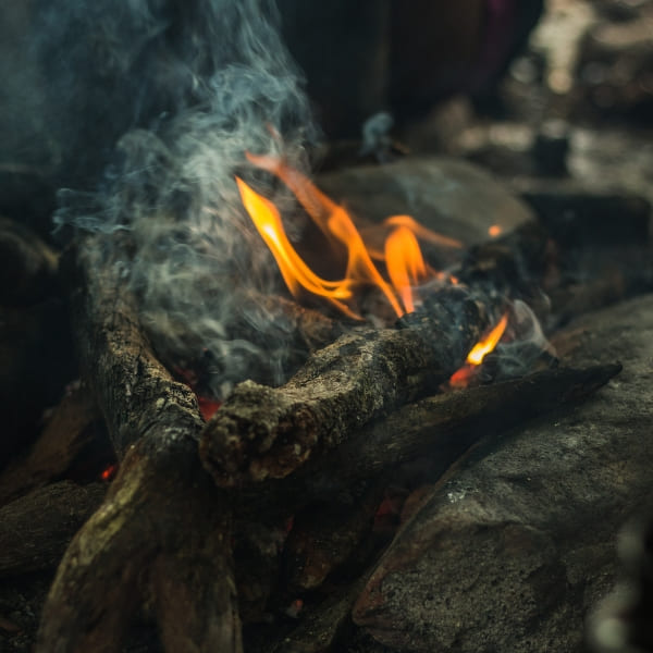 Uma pequena fogueira acesa no chão da floresta durante uma expedição de acampamento noturno na Amazônia.