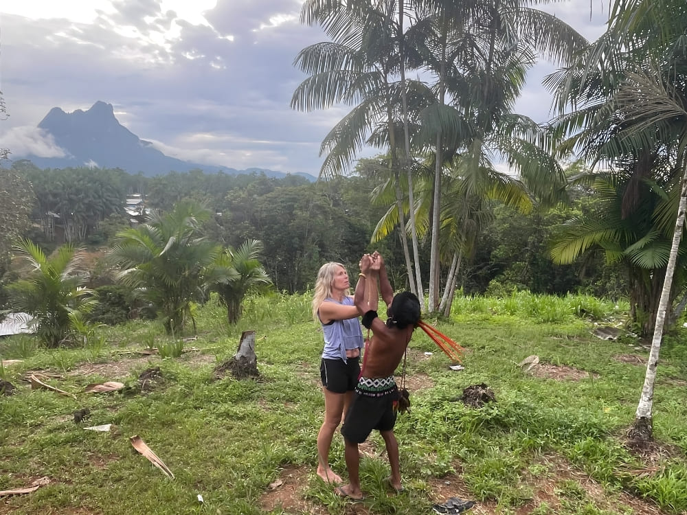  Katharina interacting in a relaxed way with a Yanomami indigenous guide in a green area, with Pico da Neblina in the background.