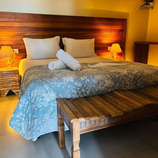 Simple and cozy hotel room with a double bed, wooden headboard, and warm lighting in Fernando de Noronha.