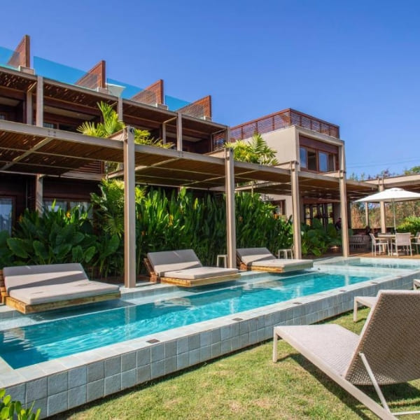 Modern hotel exterior showing a long swimming pool surrounded by sunbeds for a relaxing stay in Fernando de Noronha.
