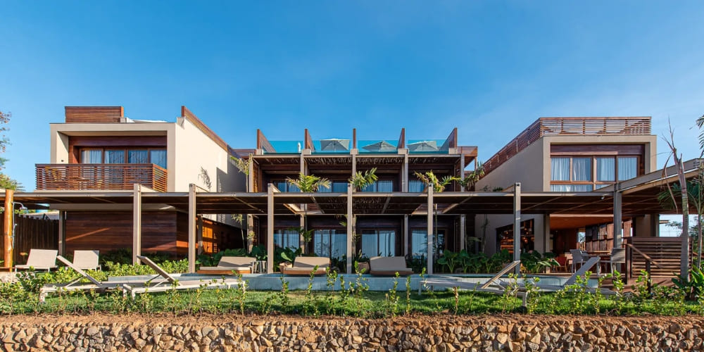 Modern exterior of Pousada Mirante featuring a long rectangular swimming pool, sun loungers, and wooden pergolas, highlighting premium hotels in Fernando de Noronha.