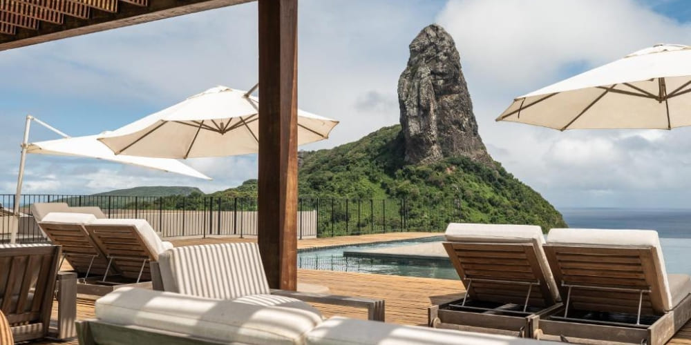  Luxury hotel deck featuring a swimming pool and comfortable lounge chairs facing the iconic Morro do Pico in Brazil.