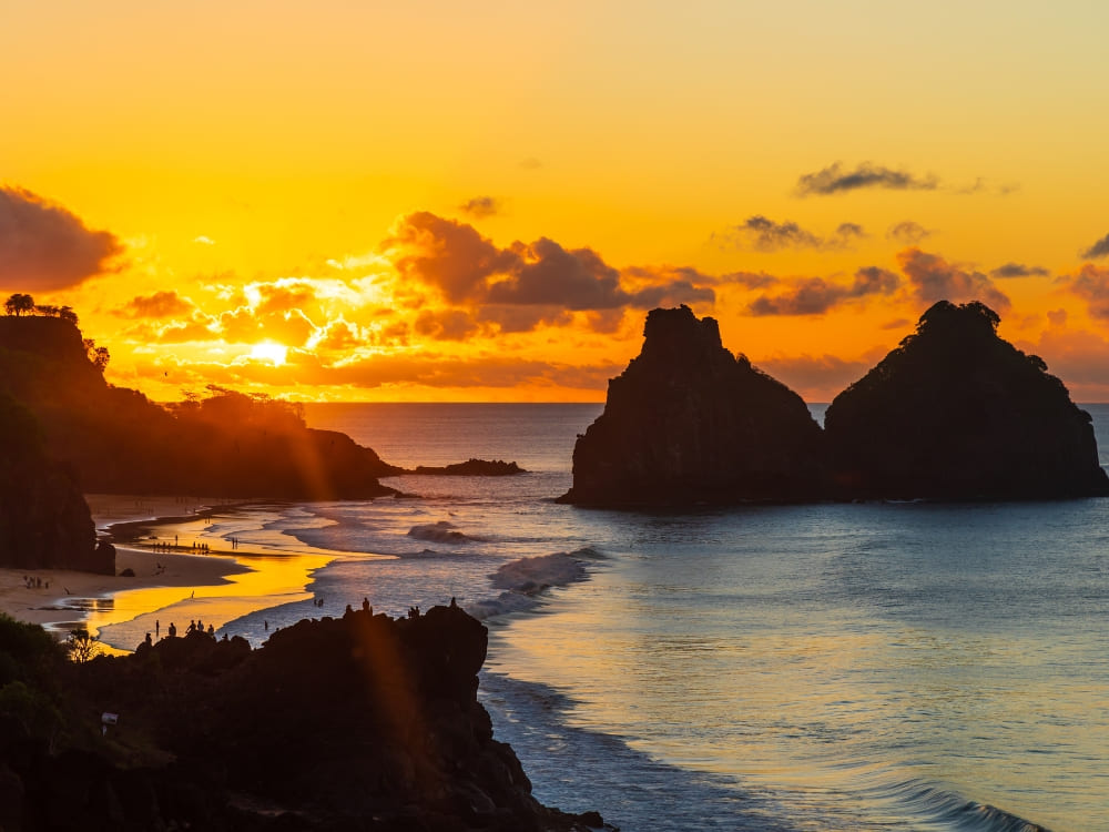 Golden sunset over the Morro Dois Irmaos rock formations, a famous landscape near hotels in Fernando de Noronha.