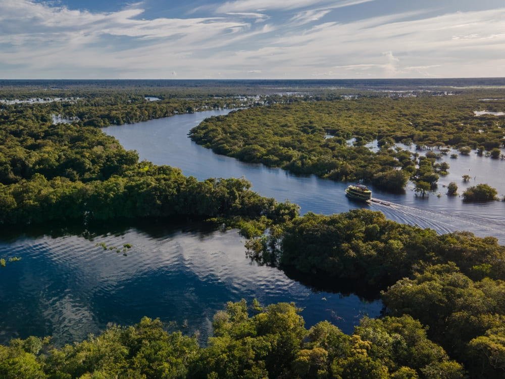 A riverboat cruising through the winding waters of the Amazon River surrounded by lush rainforest.