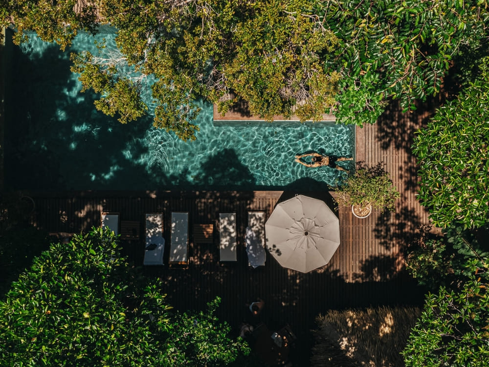 Aerial view of an Amazon jungle lodge featuring a swimming pool and wooden deck surrounded by dense trees.