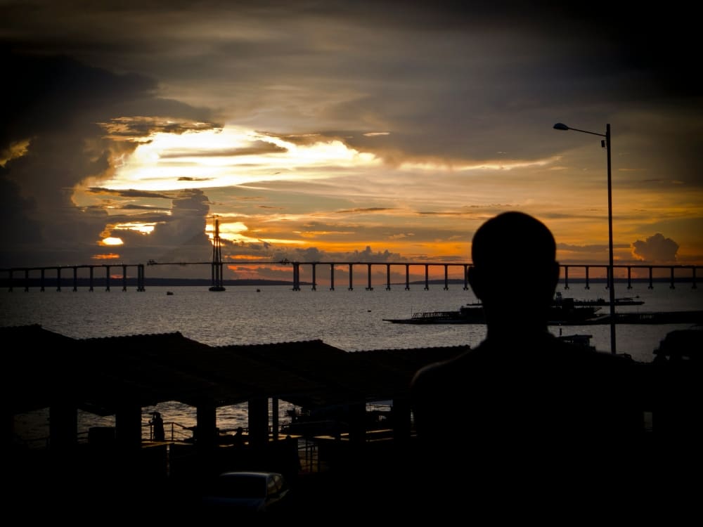 Silhouette of a traveler watching the sunset over the Amazon River from Manaus, the gateway to the rainforest. 