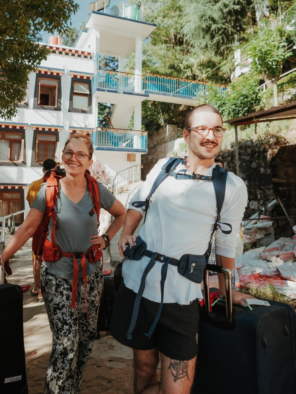 Mila and Lorenzo wearing trekking backpacks and smiling as they prepare for physical endurance on the Mardi Himal trek in Nepal.